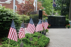 Five American flags in ground with Veteran memorial in background at Belvidere, NJ courthouse